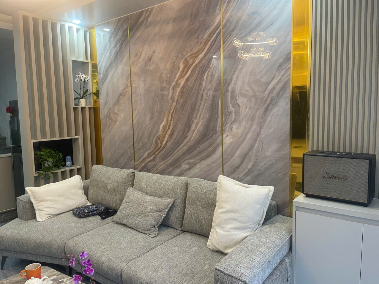 Khu vực phòng khách nhà phố với sofa xám và mảng tường vân đá trang trí