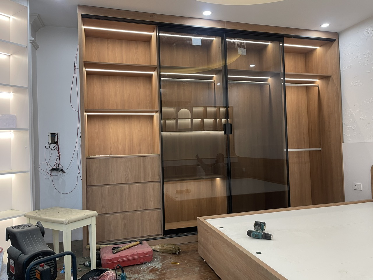 Không gian phòng ngủ với tủ quần áo cánh kính, giường ngủ và hệ tủ gỗ sáng màu
